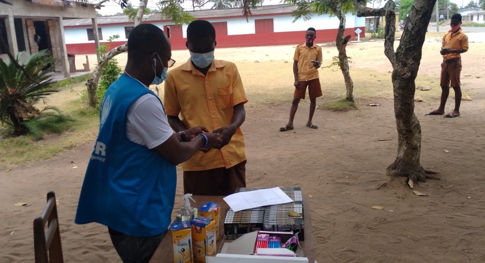 Des étudiants de dernière année font la queue pour recevoir des fournitures scolaires de la part d'un employé du HCR avant les examens du certificat d'éducation de base près du camp de réfugiés de Krisan, au Ghana. 