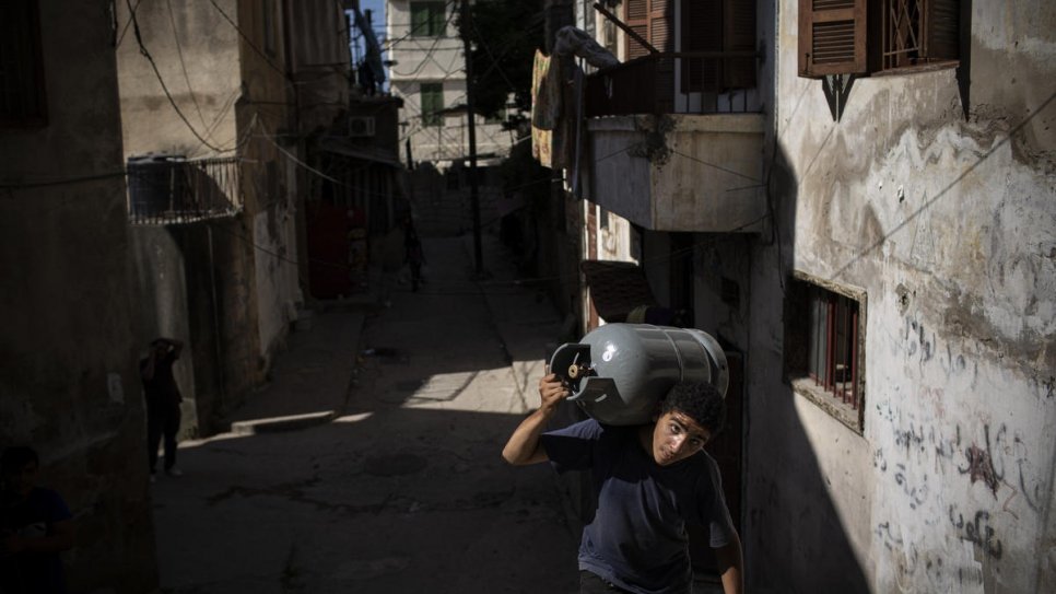 Un jeune réfugié syrien transporte un bidon de gaz dans le quartier de Bab al-Tabbaneh à Tripoli, au Liban. 