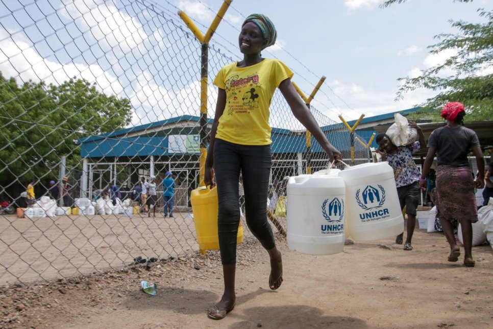 Une réfugiée sud-soudanaise vient de recevoir des jerrycans à un point de distribution au camp de réfugiés de Kakuma, au Kenya, dans le cadre de l'effort mondial de protection des réfugiés contre la pandémie de coronavirus. 