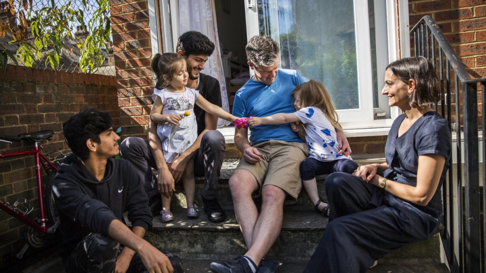 James Lynch (in blue), his daughter, and Claire Tillotson (right), from the Peckham Sponsors Refugees local residents group, hang out with Mohammed Al-Shaabin (top-left), his daughter Celen, and his brother Islam, outside their home in south London. James speaks Arabic and is the group's interpreter, while Claire is a languages teacher and helps the family with English lessons.