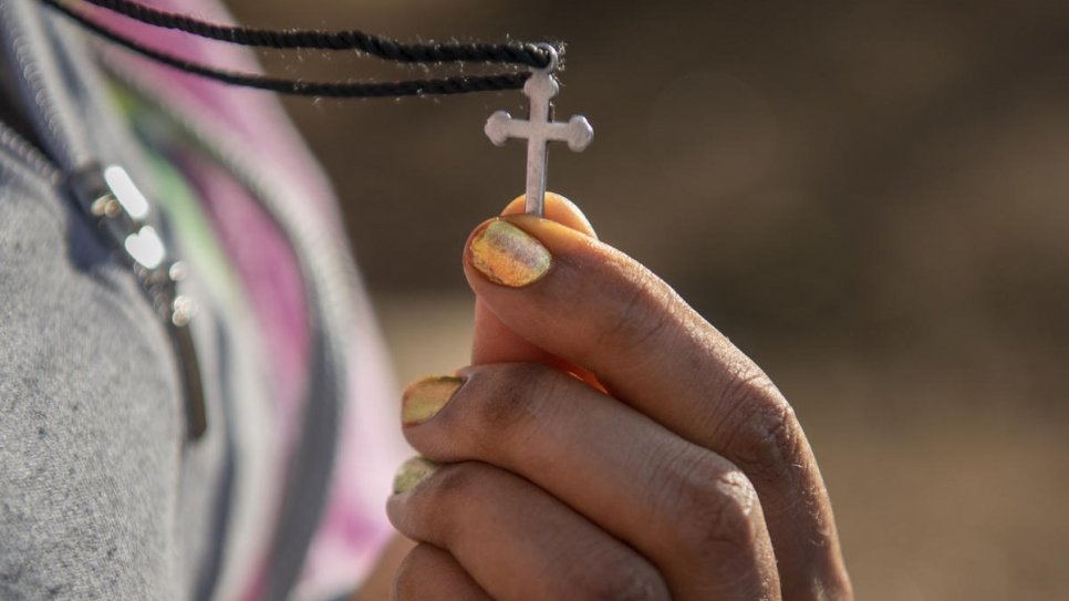 Samrawit tient un crucifix - le seul objet qui lui reste de chez elle en Erythrée - au centre de transit d'urgence du HCR à Gashora, au Rwanda.  