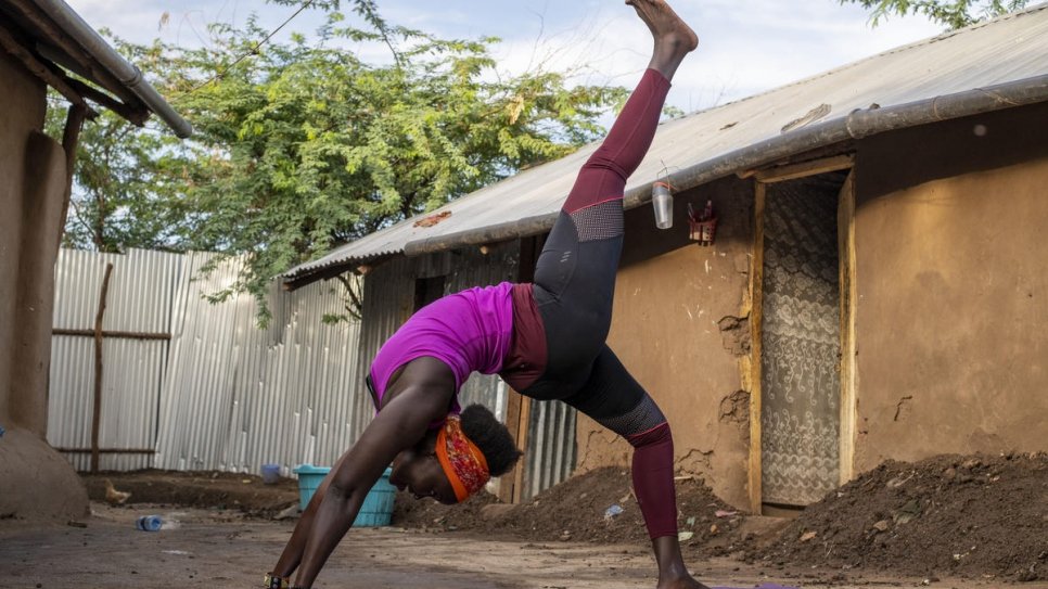Rita Brown, réfugiée ougandaise et instructrice de yoga, prend une pose de yoga à l'extérieur de son logement dans le camp de Kakuma, au Kenya. 