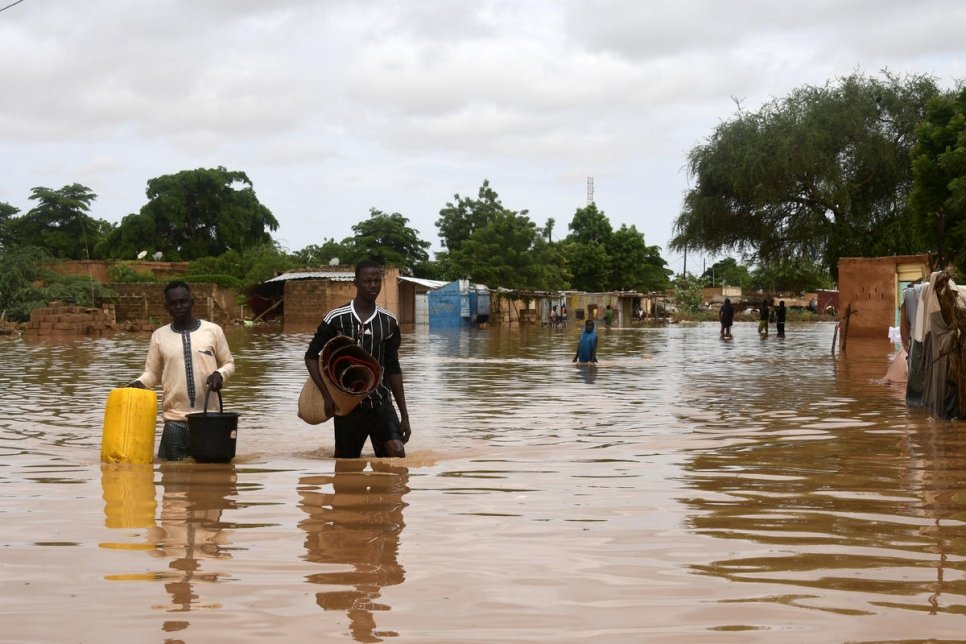 Des personnes transportent des effets personnels dans une rue inondée par le fleuve Niger dans le quartier de Kirkissoye à Niamey, au Niger le 27 août 2020. 
