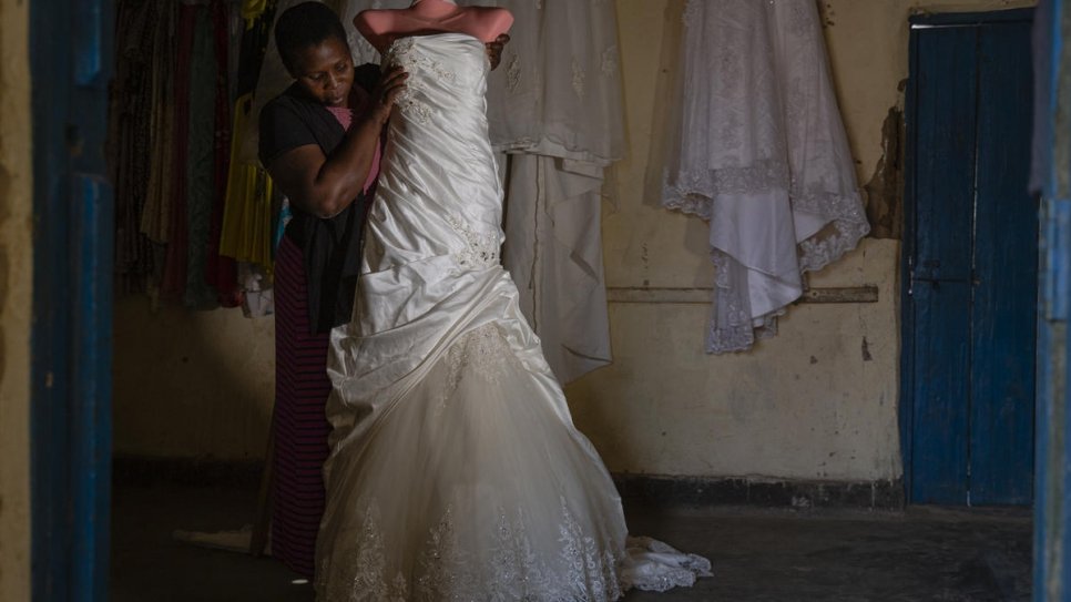 Congolese refugee Neema Claire, one of hundreds of women supported by Francoise Sabuni Chikunda, displays one of the wedding dresses she's made in Nakivale settlement, Uganda.