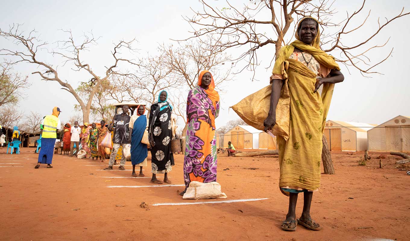 Sudanese refugees observe physical distancing while listening to health and sanitation messages over a speaker system at Ajuong Thok camp in South Sudan.