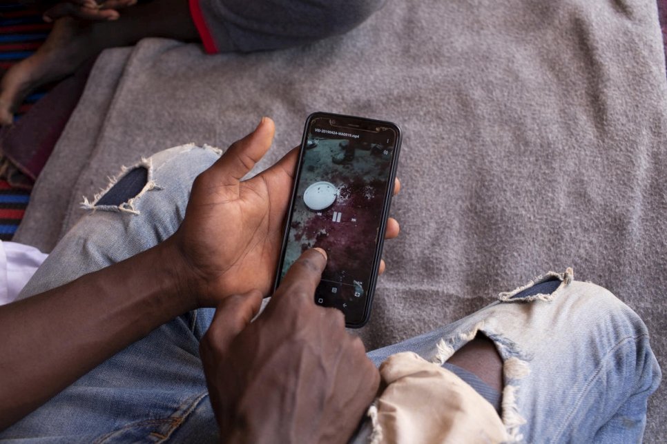 Sudanese asylum-seeker Yasir was illegally detained by a militia in Libya. Evacuated to safety in Niger, he checks his phone at UNHCR's Emergency Transit Mechanism camp outside Niamey, May 2019.