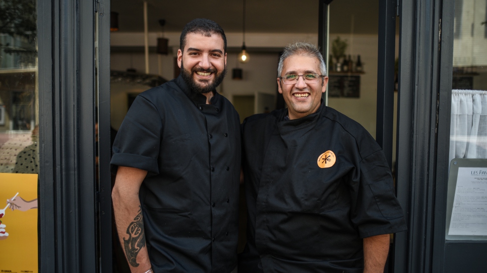 Le chef réfugié syrien, Nabil Attar (à droite), et le restaurateur parisien, Walid Sahed (à gauche), posent en face du restaurant Les Pantins à Paris, le 16 juin 2017, après avoir préparé de succulents plats à l'occasion du Refugee Food Festival 2017, soutenu et co-organisé par le HCR depuis sa création en juin 2016.
