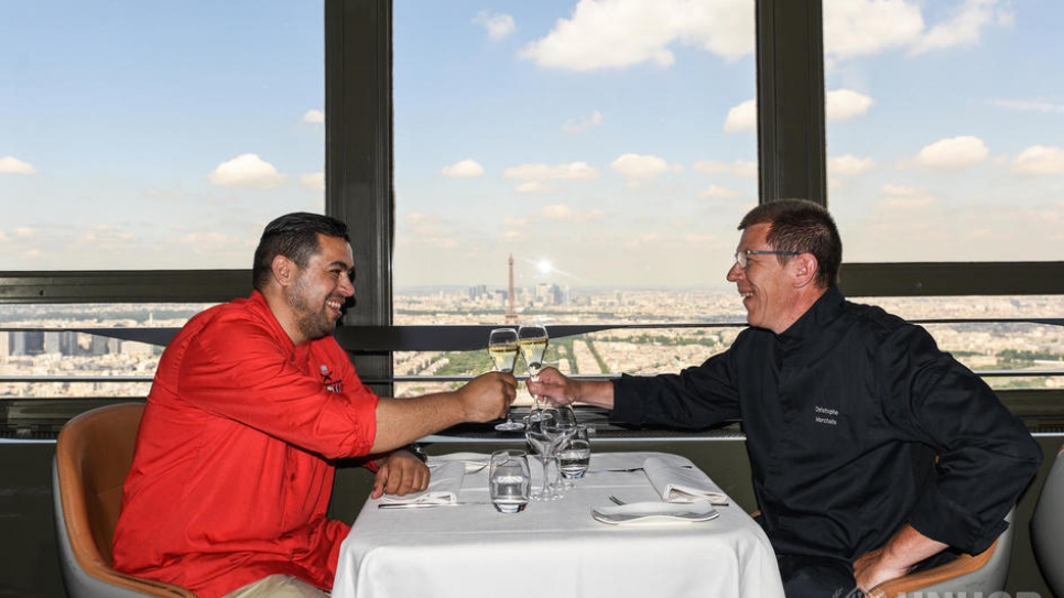 Le chef syrien réfugié Mohammad El Khaldy et son homologue français Christophe Martin trinquent avant de ravir les gourmands au Ciel de Paris lors du Refugee Food Festival de Paris. Avant de fuir la guerre dans son pays, Mohammad El Khaldy était un  célèbre chef et animateur d'une émission culinaire à la télévision syrienne. 
