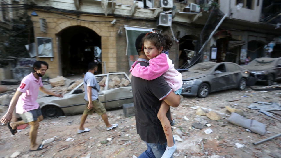 Un homme transporte une enfant blessée vers un lieu sûr à la suite d'une explosion massive dans le port de Beyrouth, au Liban. 