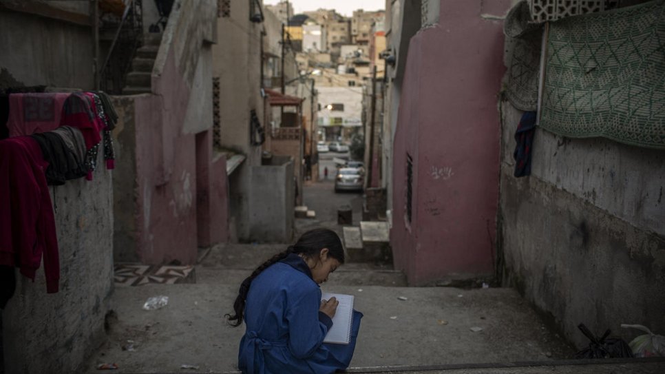 Eleven-year-old Namaat writes a poem on the steps outside her home. 