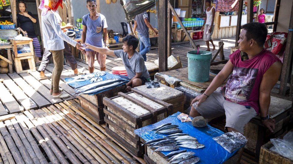 Les résidents vendent du poisson sur les étals de la communauté de réinstallation de Valle Vista, près de Zamboanga, Philippines. La communauté est composée de deux groupes ethniques, les Sama Bajau et les Tausug. 