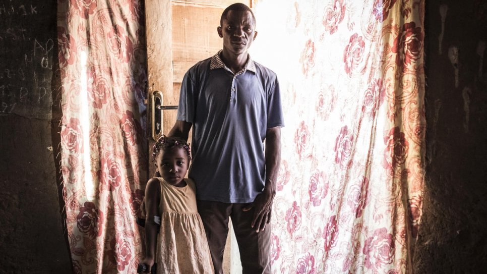 Chadrack Neta se tient avec sa fille dans sa maison à Tshikapa en République démocratique du Congo. Il est revenu d'Angola avec sa famille en octobre dernier