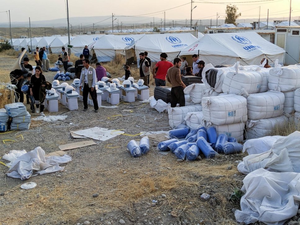 Des réfugiés syriens collectent des couvertures et d'autres articles de première nécessité auprès du personnel des organisations partenaires du HCR au camp de Bardarash à Dohouk en Irak.