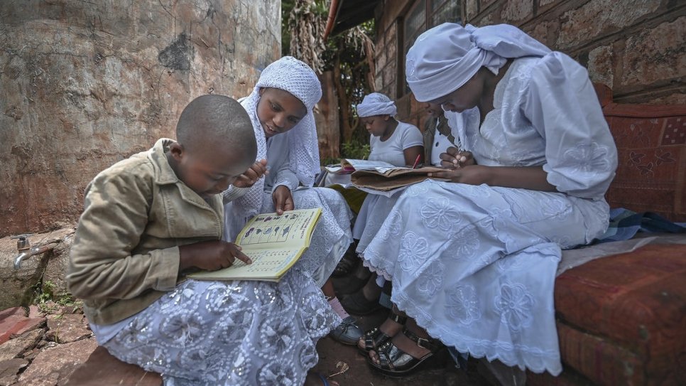 Nosizi Reuben (second from left), assists her sisters with their studies, outside their home in Kinoo, Kenya.