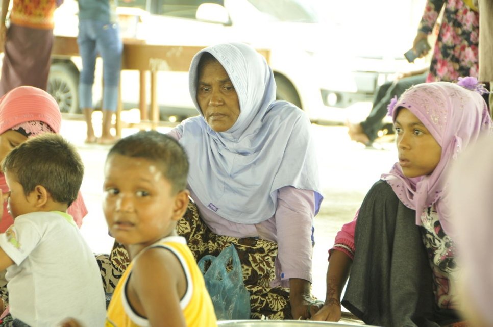 A small group of women and children sit on the floor.