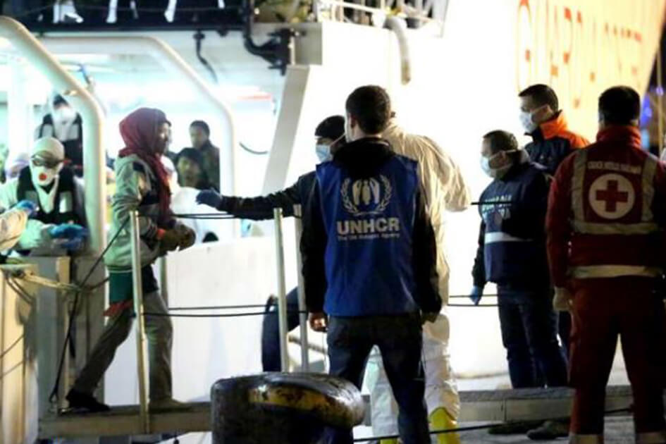 Operatori UNHCR e della croce rossa che aiutano lo sbarco di rifugiati