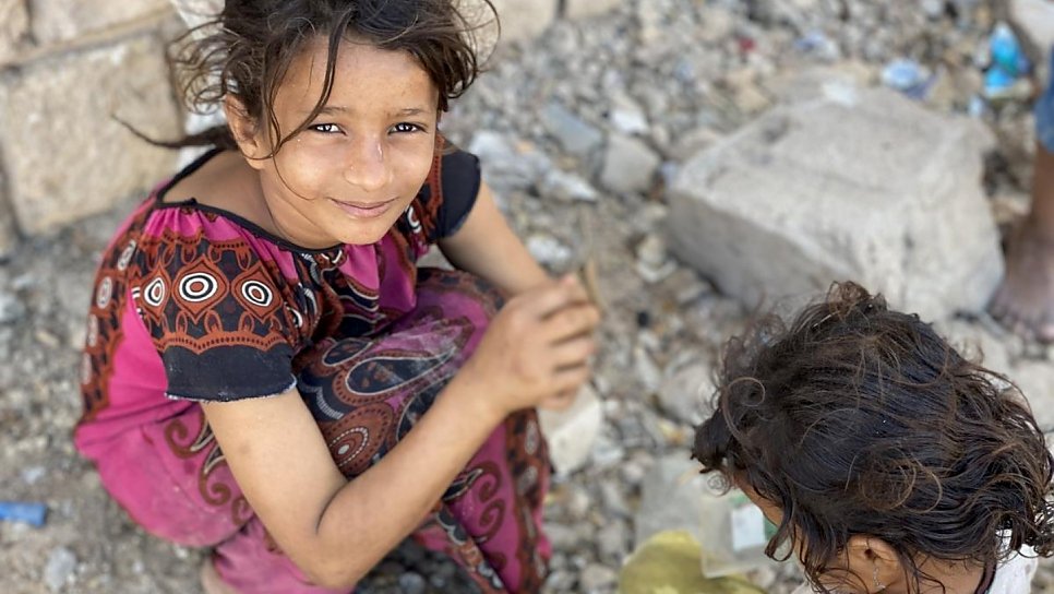Nesta foto de fevereiro de 2020, Ipteehal, 9, brinca com sua irmã do lado de fora do prédio inacabado, onde moram com outras famílias deslocadas em Al Mukalla, no Iêmen