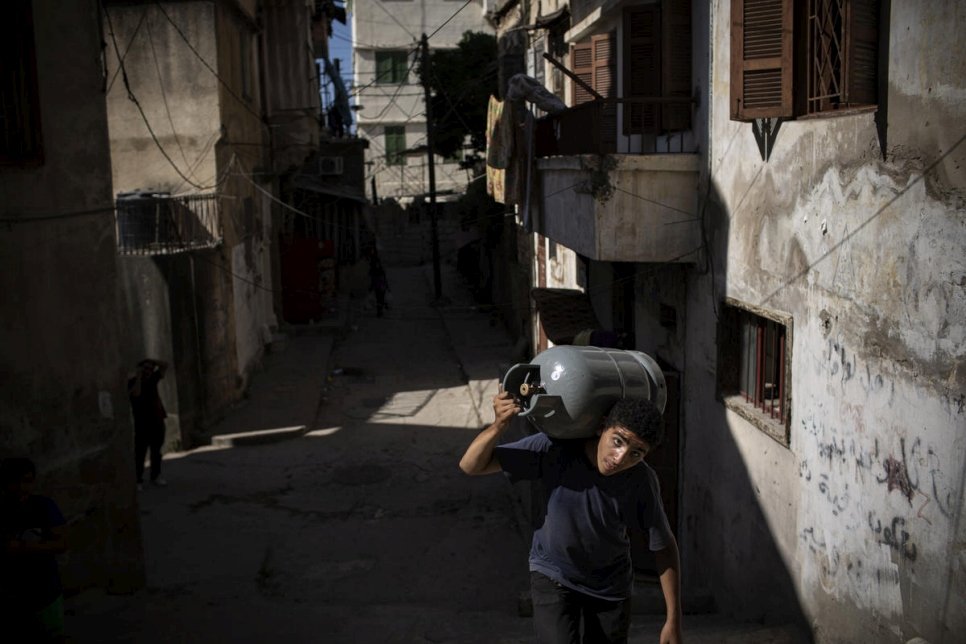 لاجئ سوري شاب يحمل عبوة الغاز في حي باب التبانة في طرابلس، لبنان. 