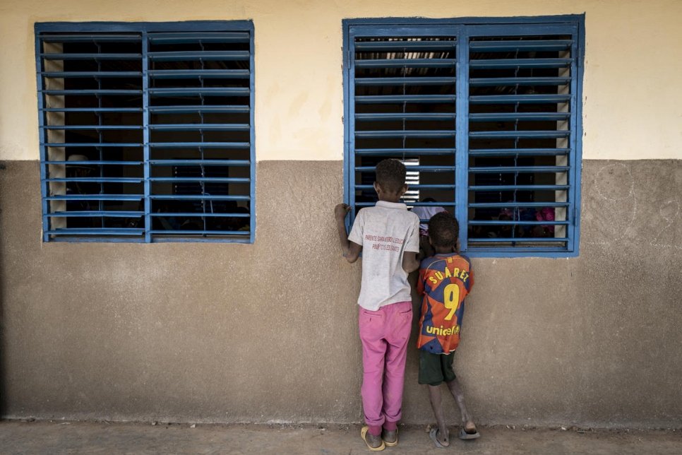 Deux jeunes Maliens regardent l'intérieur d'une salle de classe depuis l'extérieur, dans une école du camp de réfugiés de Goudoubo au Burkina Faso, où l'insécurité croissante avait forcé les enseignants à rester chez eux dès la fin 2019. Photo d'archives. 