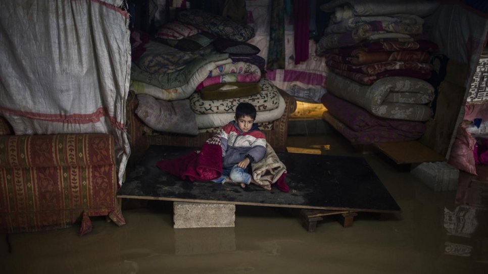 One of Juriya Ramadan's sons sits inside his flooded tent. The tent collapsed as a consequence of Storm Norma's violence.