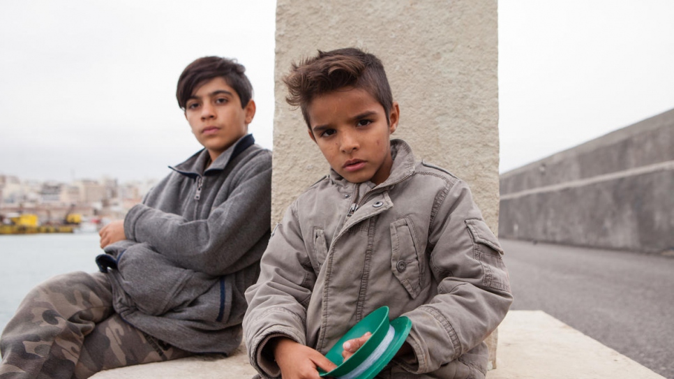 Wahid, de 12 años, y Navid, de 7, están aprendiendo a pescar en el puerto.