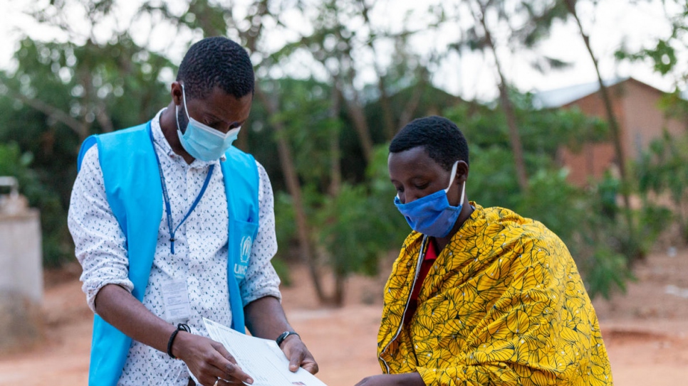 A UNHCR staffer checks the documents of Burundian refugee Claudine Habimana before she departs from Rwanda. 