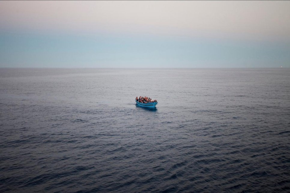 Une embarcation bondée, avec des réfugiés et des migrants à son bord tentant de rejoindre l'Europe, vue depuis le pont d'un navire des garde-côtes italiens, le San Giorgio, pendant une patrouille en mer Méditerranée en 2014. 