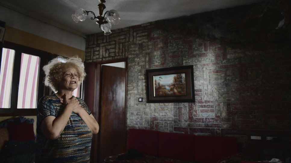 Lebanese Odette Bassil, 73, stands in the living room of her home in Beirut, damaged by the explosion.