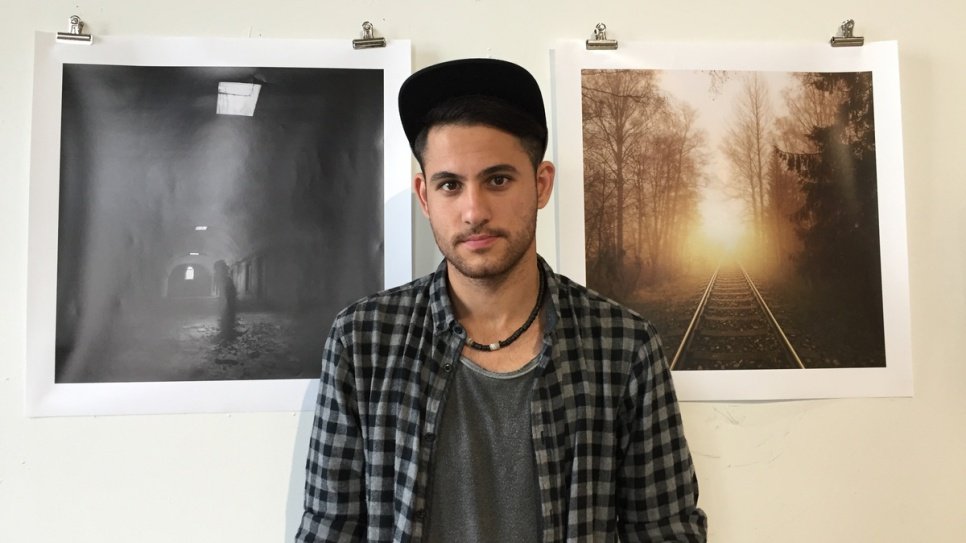 Ahmed debout devant des photos qu'il a prises en Iraq et en Finlande, lors de son exposition à Helsinki. 