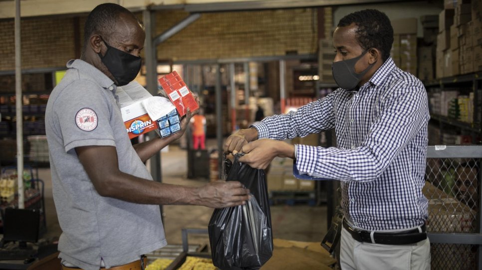 Amin Sheikh (right) hands a bag of items to a vulnerable South African during a food distribution in Pretoria, South Africa.