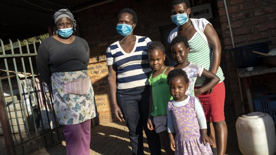 Une famille zimbabwéenne se tient devant son logement dans le nord de Pretoria après avoir reçu de la nourriture de la communauté des réfugiés somaliens. 