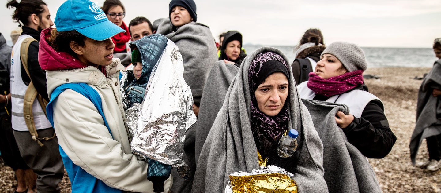 A UNHCR staff member helps a family of refugees who have just disembarked from a boat carrying them from Turkey to the Greek island of Lesbos.