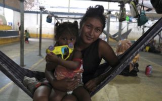 A woman and child from Venezuela sit on a hammock