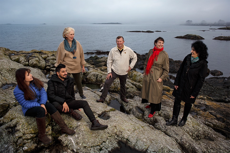 Group of people sitting on a rocky coast by the ocean