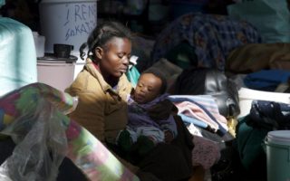 Mother holds child among clutter in South Africa