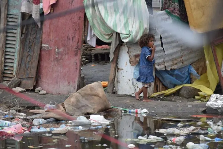 A child walks past flood water at a site for internally displaced people in Aden, Yemen, March 2020