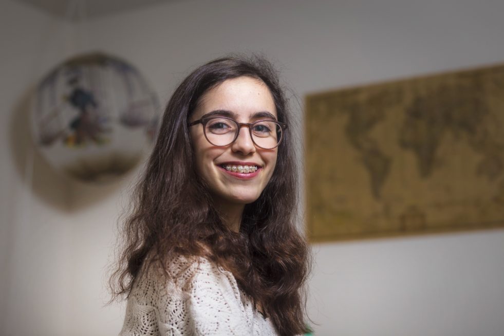 A young girl with glasses and braces smiles at the camera