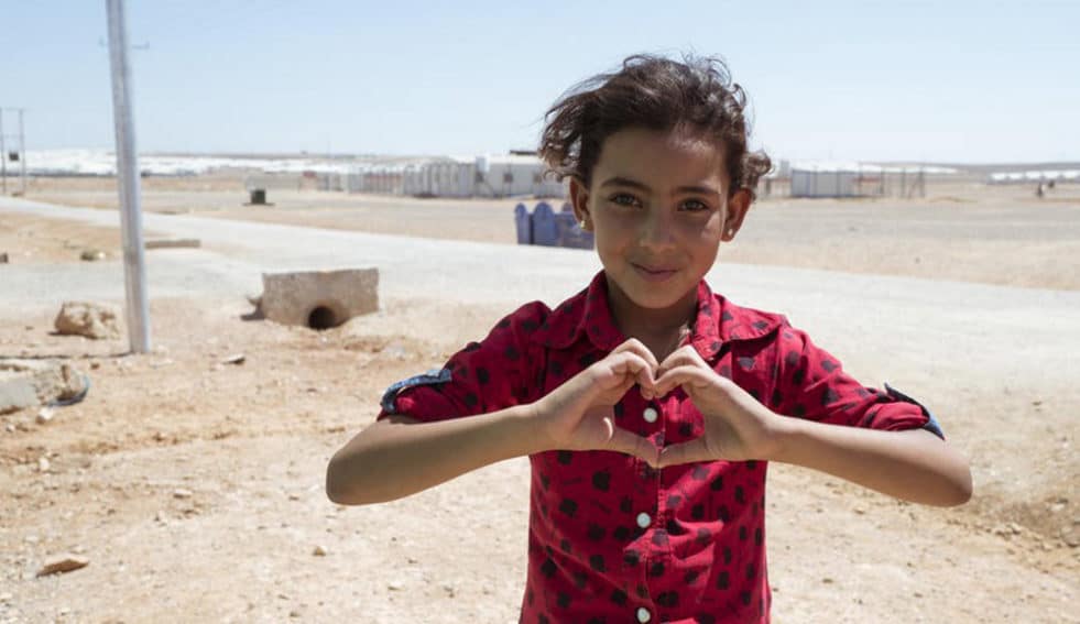 Portrait of a young girl making a love heart with her hands