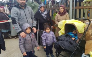 Syrian family of six poses in front of a crowd of people