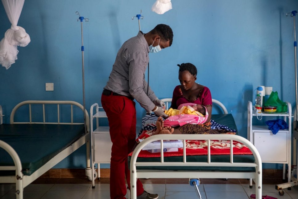 Un travailleur de santé prodigue des soins à une réfugiée burundaise âgée de 23 ans et à son nouveau-né, après la naissance de la petite fille au centre de santé de Natukobenyo dans l'installation de Kalobeyei, au Kenya. Octobre 2020.