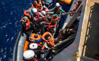 People try to climb onto a boat