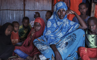 Somali woman sits in a room surrounded by her children