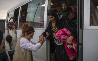 People in Syria board a bus