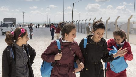 Turkey / Ivra (wearing purple jacket) walks back to her families tent with friends after school in Suruc camp. Ivra, 13, is just one of the 4 million Syrians made refugees by a conflict that recently entered its fifth year. Displaced along with her two sisters and parents from the Syrian border town of Kobane, she now lives as refugee in Turkey's largest refugee camp in Suruc./ UNHCR / I. Prickett / April 2015 ; In Kobane, Ivra and her family were solidly middle-class; they lived in the city centre in a modern, three-bedroom house. Now, in Suruç camp, Ivra says she spends most of her free time watching movies. The films that once helped her learn a new language are now just filling time. Her only regular activity besides attending school is acting in a play with a small theater group.