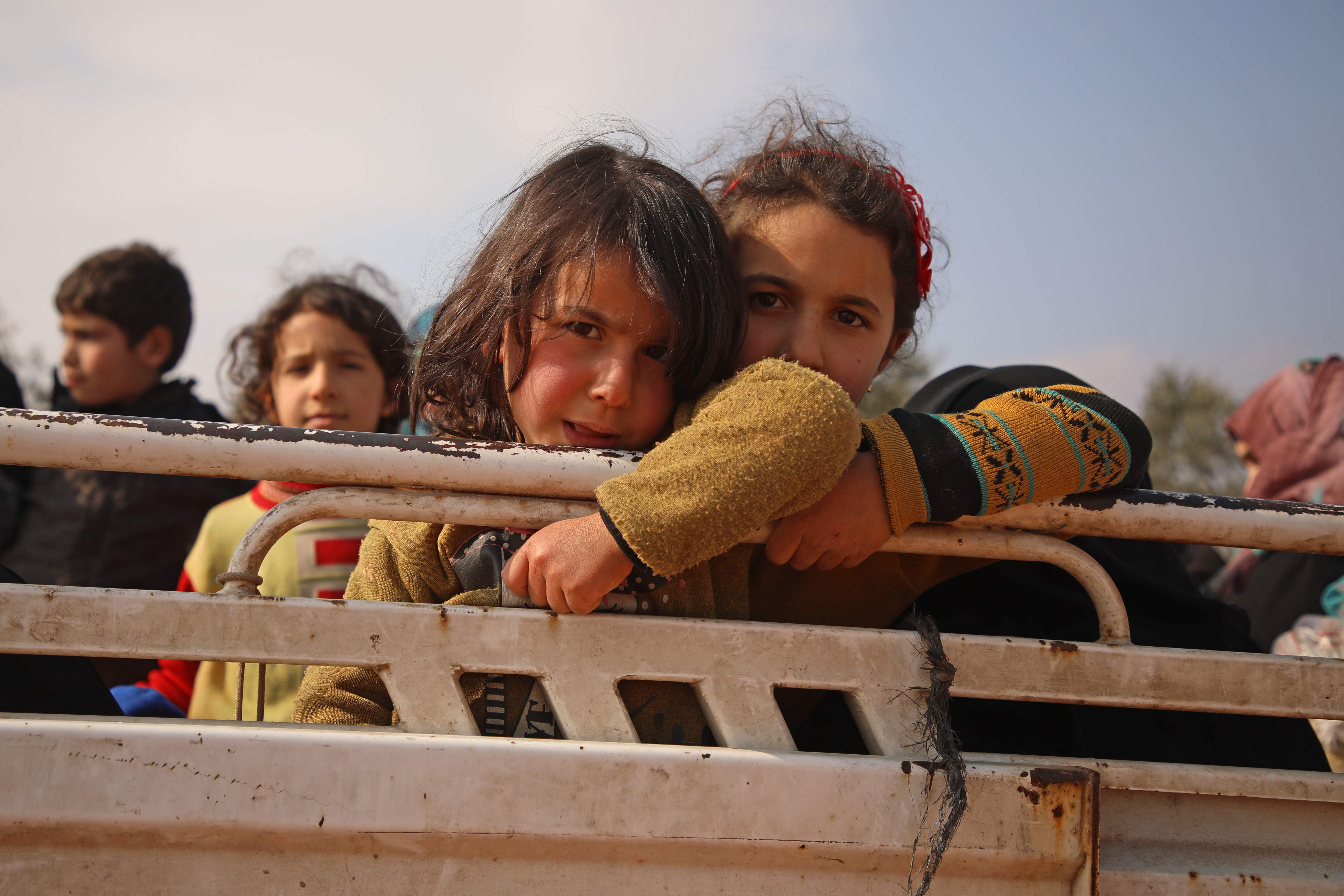 Syria. Displaced Syrian girls stand in the back of a truck parked at a newly-established camp