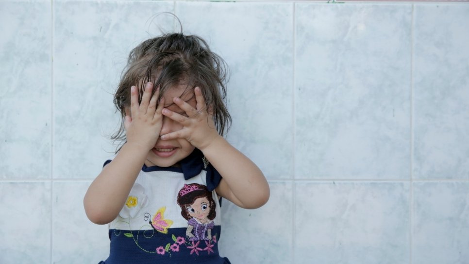 A young girl cover her eyes with her hands
