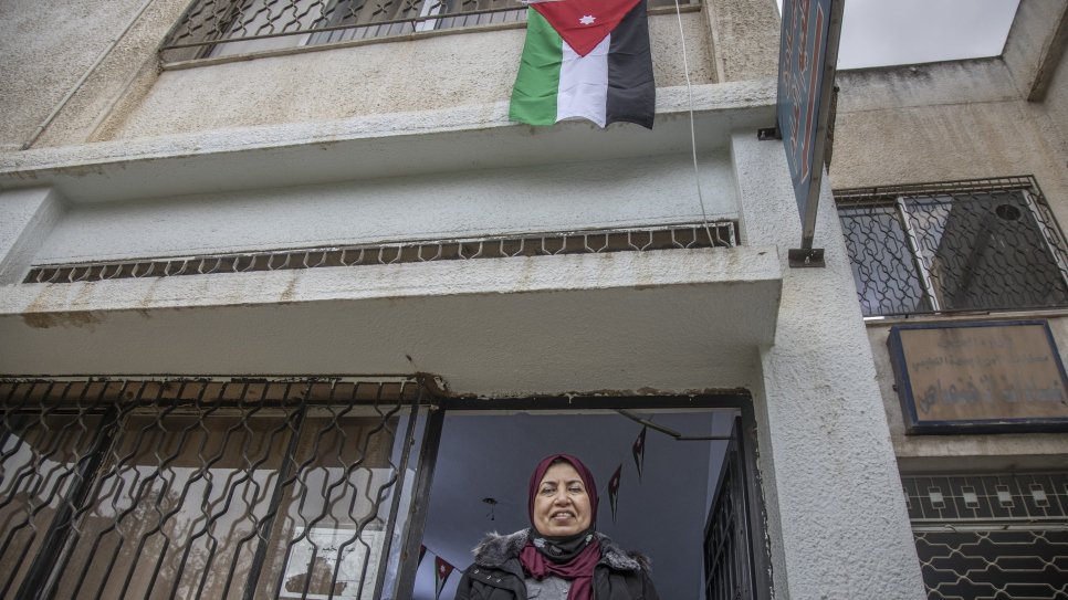 Raia AlKabashi stands under the flag of Jordan outside the health centre in Irbid where she received her COVID-19 vaccine.