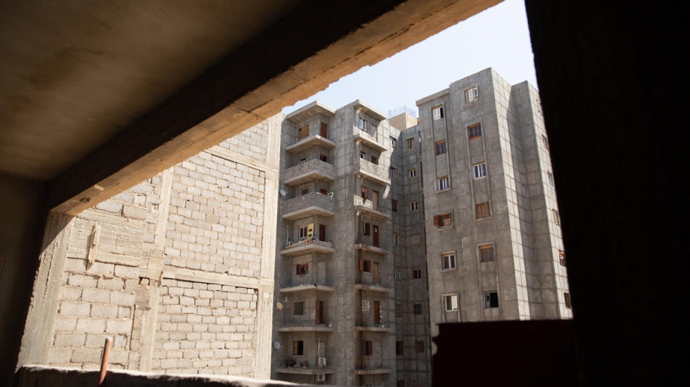 An unglazed window in Hanan's apartment overlooks other unfinished buildings which currently host more than 100 uprooted Libyan families.