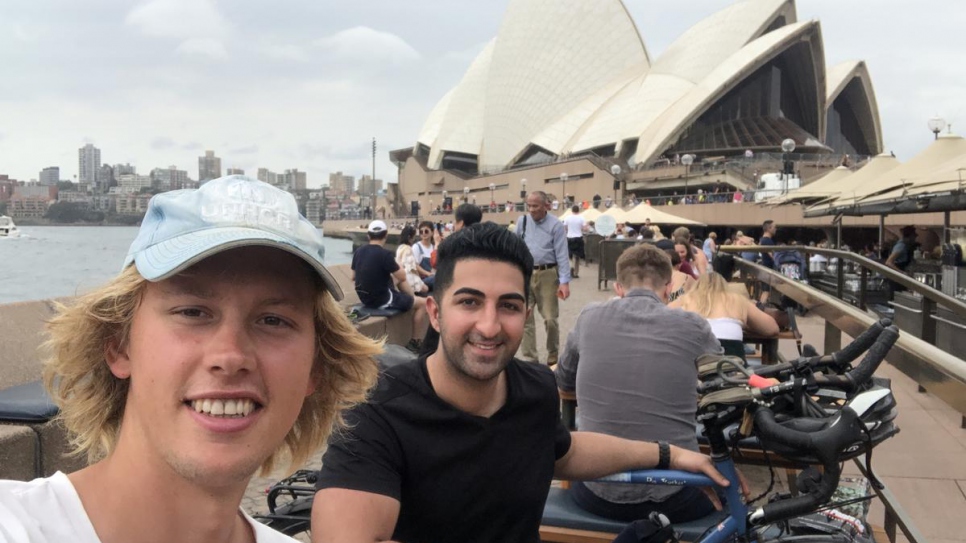 Cyclist Theo Foster meets Iranian refugee and co-chair of UNHCR's Global Youth Advisory Council, Arash Bordbar at Sydney Opera House, Australia.