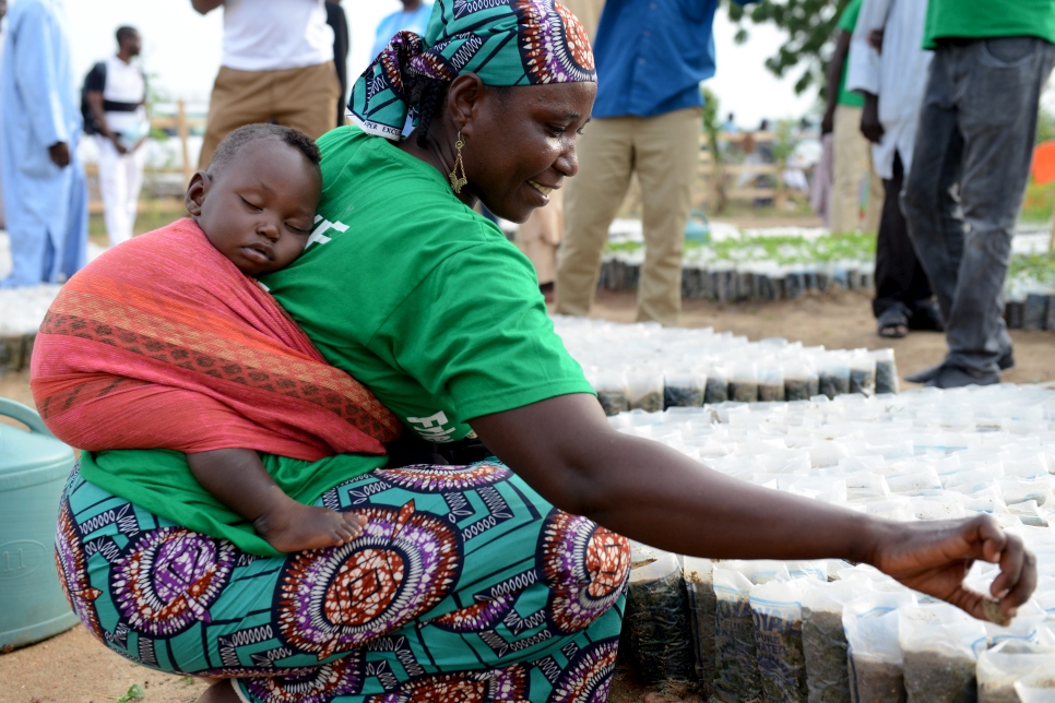 A Nigerian mother carrying her baby on her back plants seeds in a nursery at Minawao refugee camp in Cameroon, as part of the reforestation project, Make Minawao Green Again.